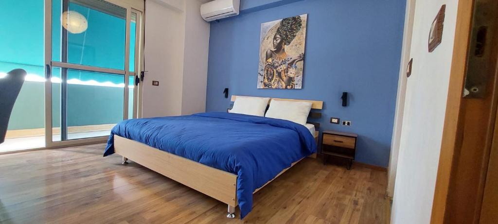 een blauwe slaapkamer met een bed en een raam bij What's Up Tirana in Tirana