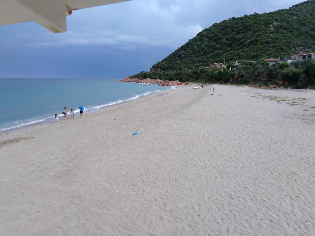 een groep mensen die op een strand lopen bij La Finestra Sul Mare in Lanusei