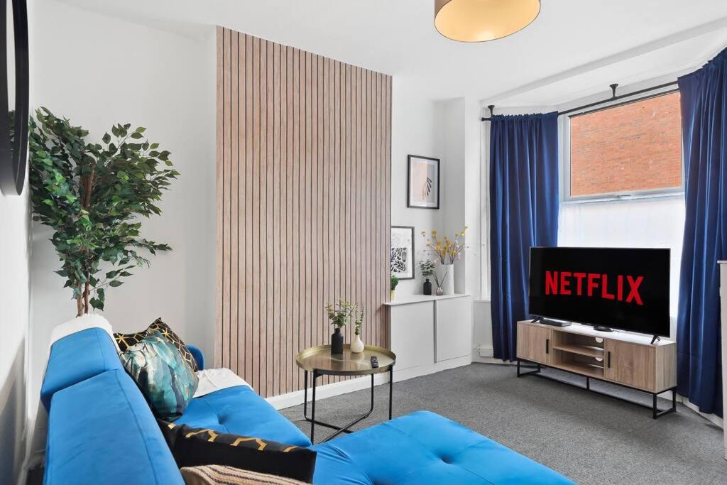 a living room with a blue couch and a television at The Scandi Gem of Nottingham - Sleeps 10 in Nottingham