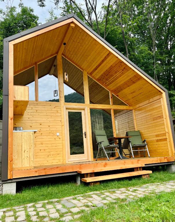 a large wooden house with two chairs and a table at Cabana Bahna 2 in Orşova