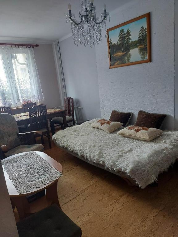 a bedroom with two beds and a table and a chandelier at Mieszkanie do wynajęcia w Centrum in Olecko