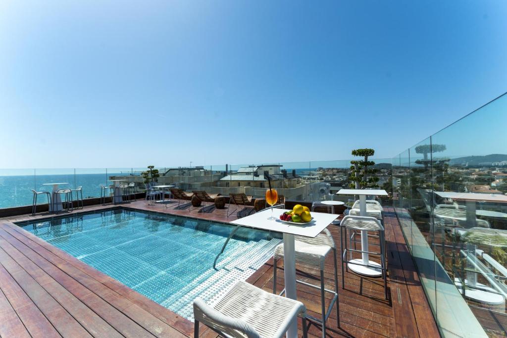 
a pool with chairs and tables in it at Hotel MiM Sitges & Spa in Sitges
