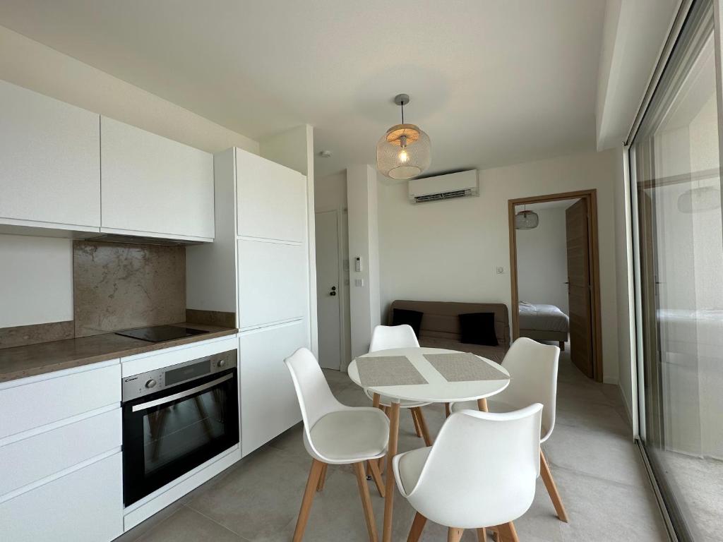 une cuisine avec des armoires blanches et une table et des chaises dans l'établissement Superbe T2 en dernier étage, à Antibes