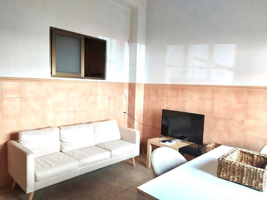 a living room with a white couch and a tv at Apartamento Perelló in El Perelló