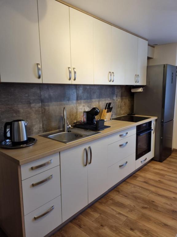 eine Küche mit weißen Schränken und einem Waschbecken in der Unterkunft KANTO - self check in in Klaipėda