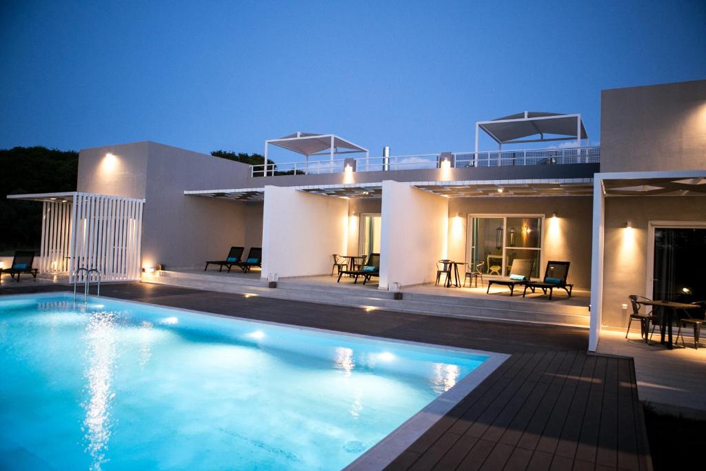 a villa with a swimming pool at night at Galinio Boutique Apartments in Skafidia