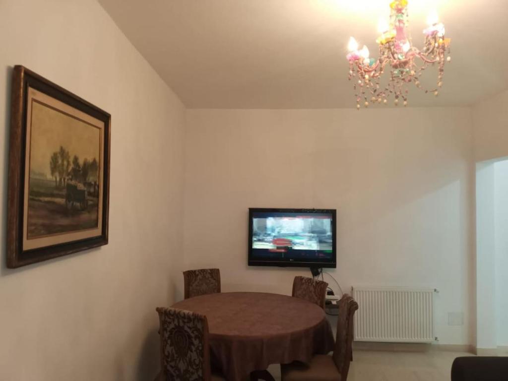 una sala da pranzo con tavolo e lampadario pendente di Appartement propre près de l'ENIS a Sfax
