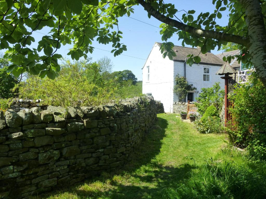 una pared de piedra frente a una casa blanca en Middlehope Cottage, en Bishop Auckland