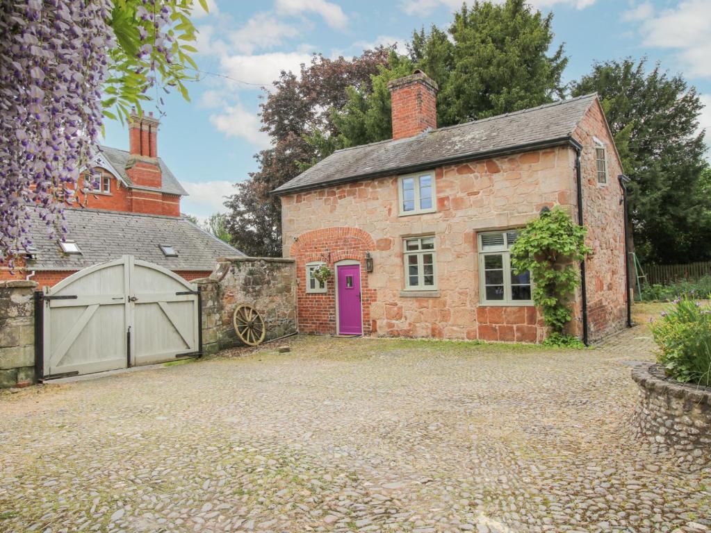 uma velha casa de tijolos com uma porta roxa e uma garagem em Rectory Cottage em Oswestry