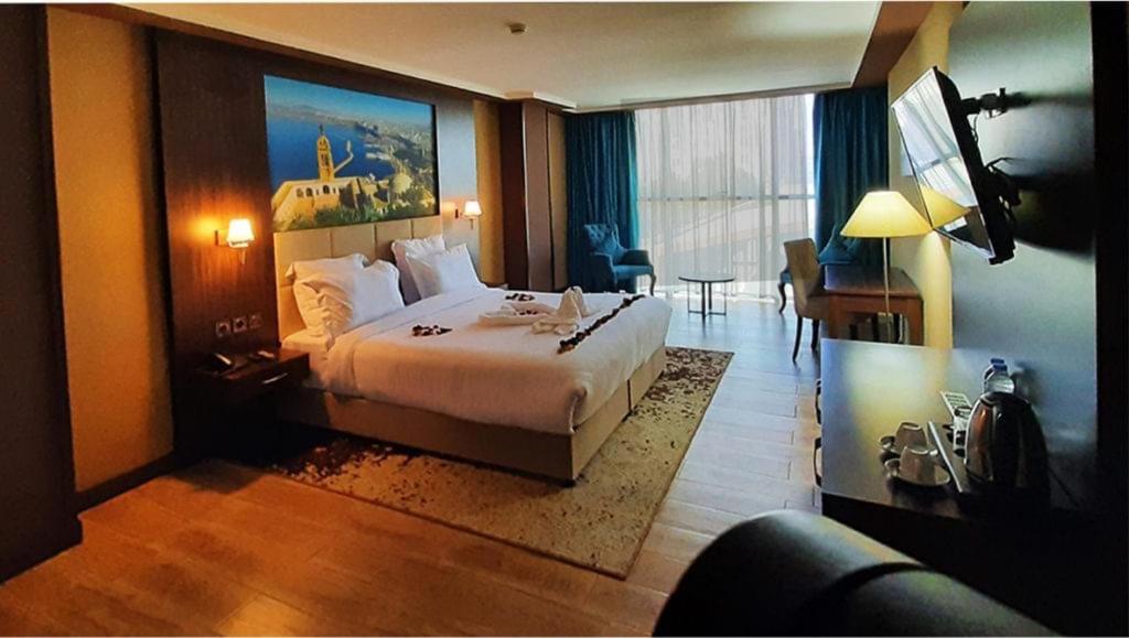 een hotelkamer met een groot bed en een bureau bij LB Suites Hotel in Bir el Djir