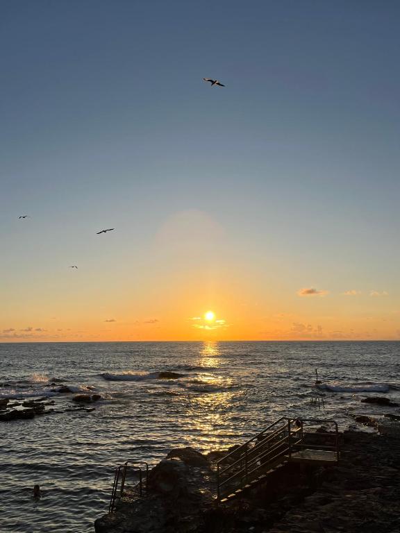 a sunset over the ocean with the sun setting at Sunset Dream, casa en la playa con terraza in Las Lagunas
