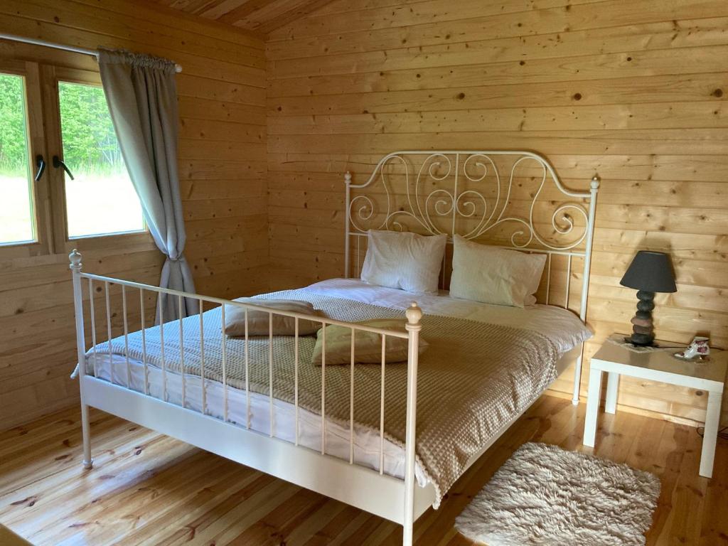 1 dormitorio con 1 cama blanca en una cabaña de madera en Zarasaičio ežero sodyba, en Magučiai