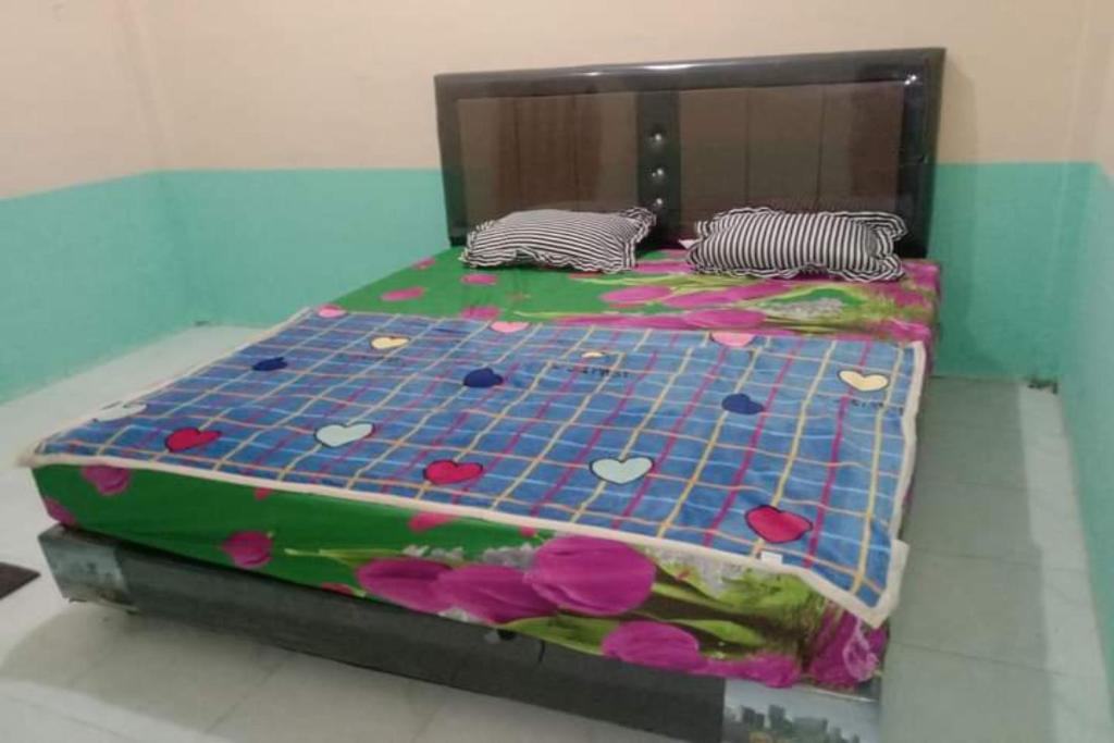 a bed with a bedspread with flowers on it at EXPRESS O 91938 Grace Kost & Hostel in Balangdua