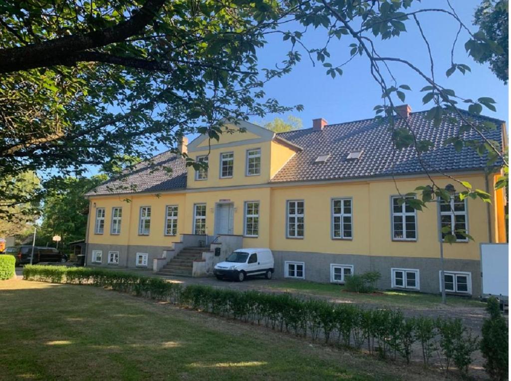 a yellow house with a car parked in front of it at Gutshausferien im Ostseehinterland 