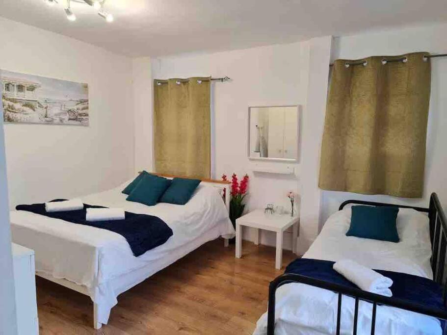 a bedroom with two beds and a table with a night stand at Nice Flat near Central London in London