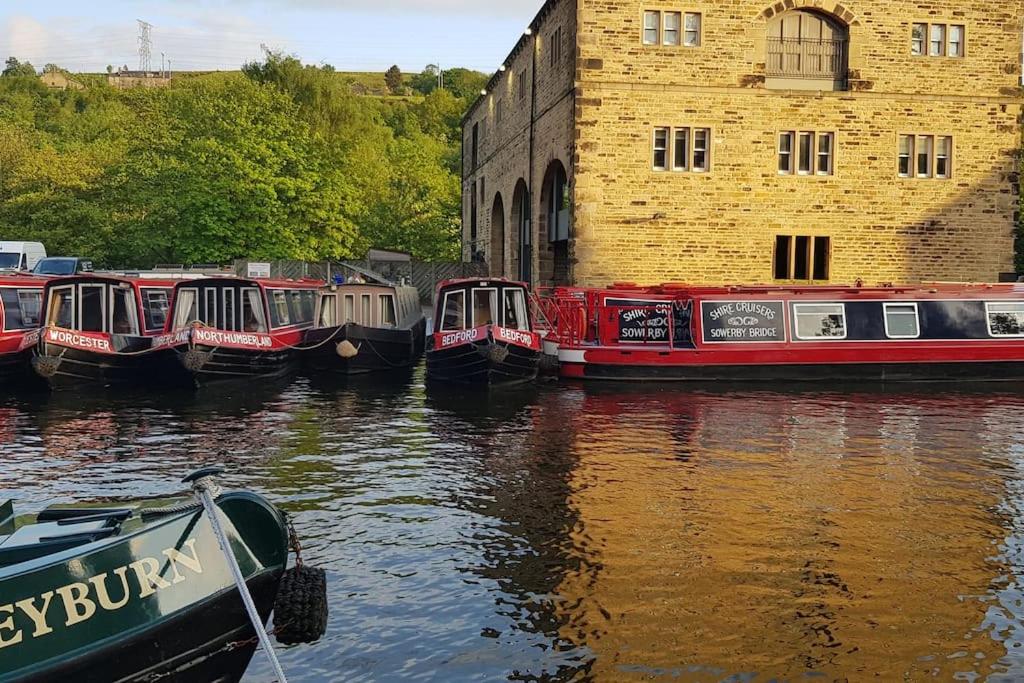a group of boats docked in a river next to a building at Bowie's Abode in Sowerby Bridge