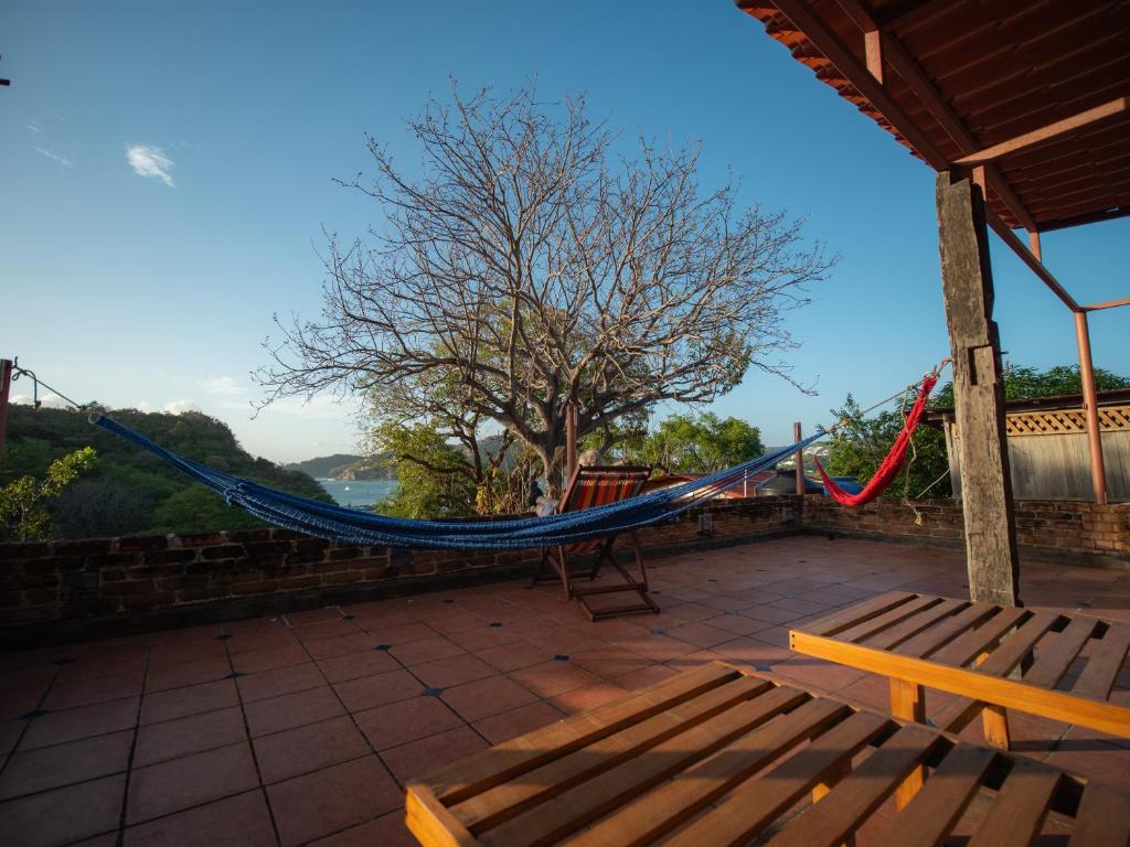 a hammock on the roof of a house with a tree at 2 bedroom apartment with bay view, deck and roof terrace in San Juan del Sur