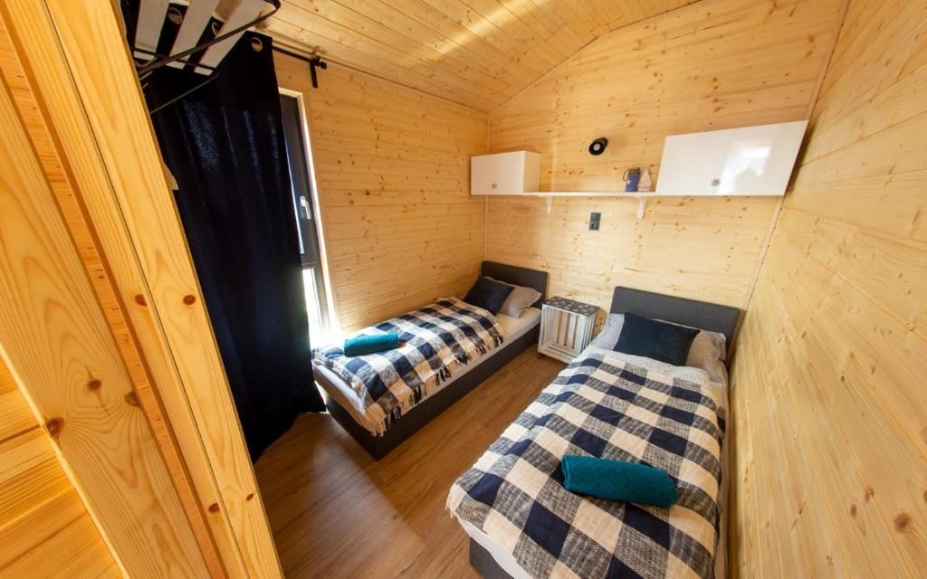 a room with two beds in a wooden cabin at Wiatr i Woda Wdzydze in Wdzydze Kiszewskie