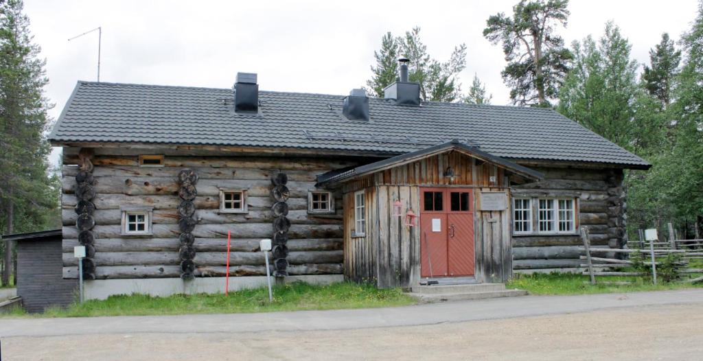 a small wooden cabin with a red door at Kuukkeli Apartments Pikku-Hirvas ja Porotokka in Saariselka