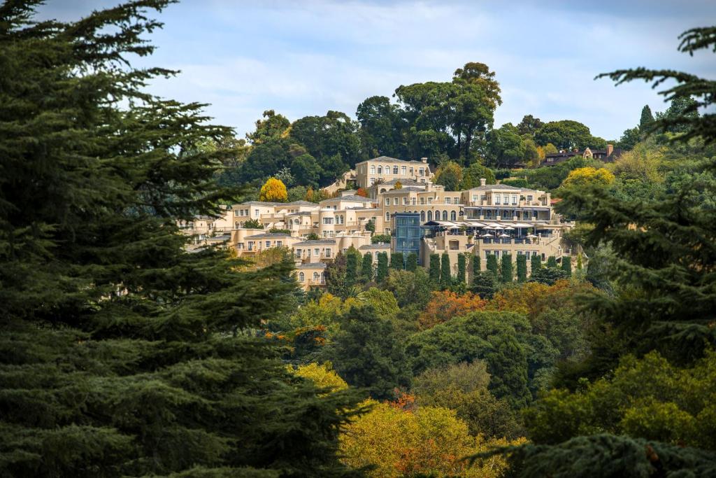 une grande maison sur une colline entourée d'arbres dans l'établissement Four Seasons Hotel The Westcliff, à Johannesbourg