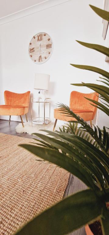 a living room with a clock and chairs and a plant at Home In Harrow/Wembley in Harrow on the Hill