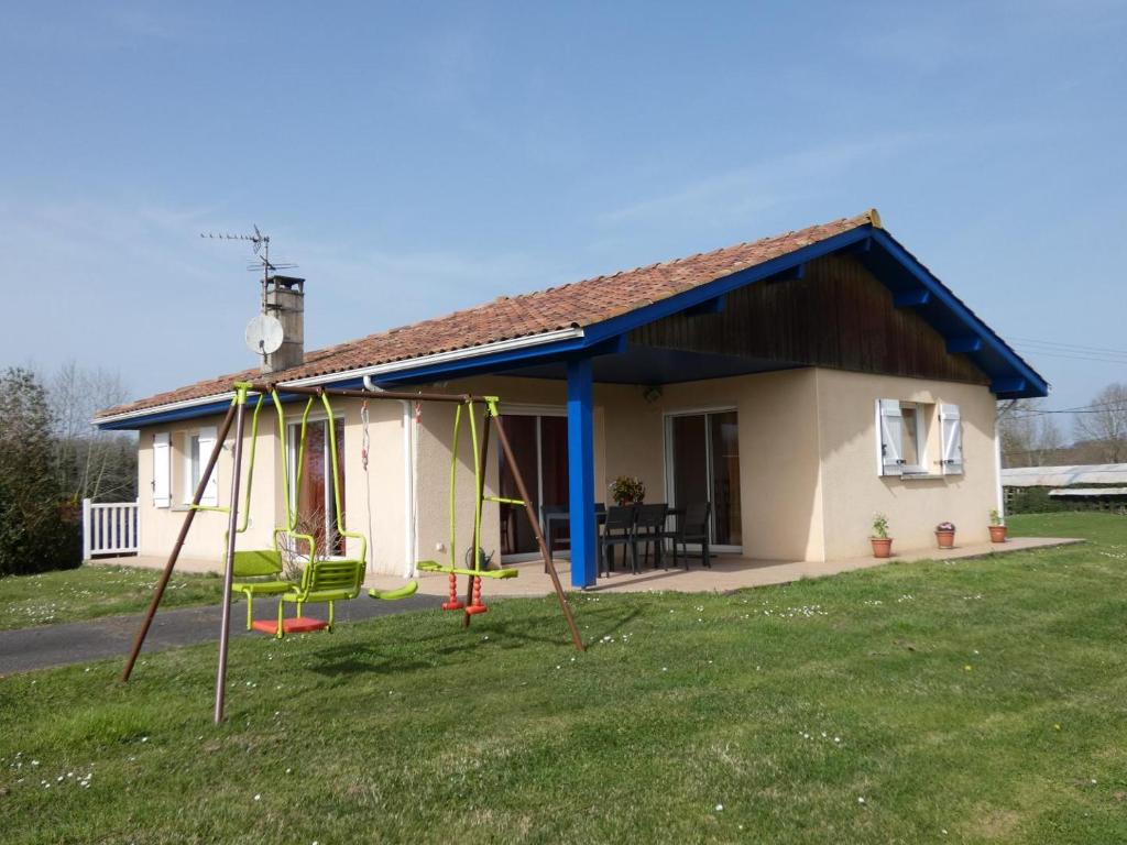 une petite maison avec une balançoire dans la cour dans l'établissement Le saoutot, à Saint-Jean-de-Marsacq
