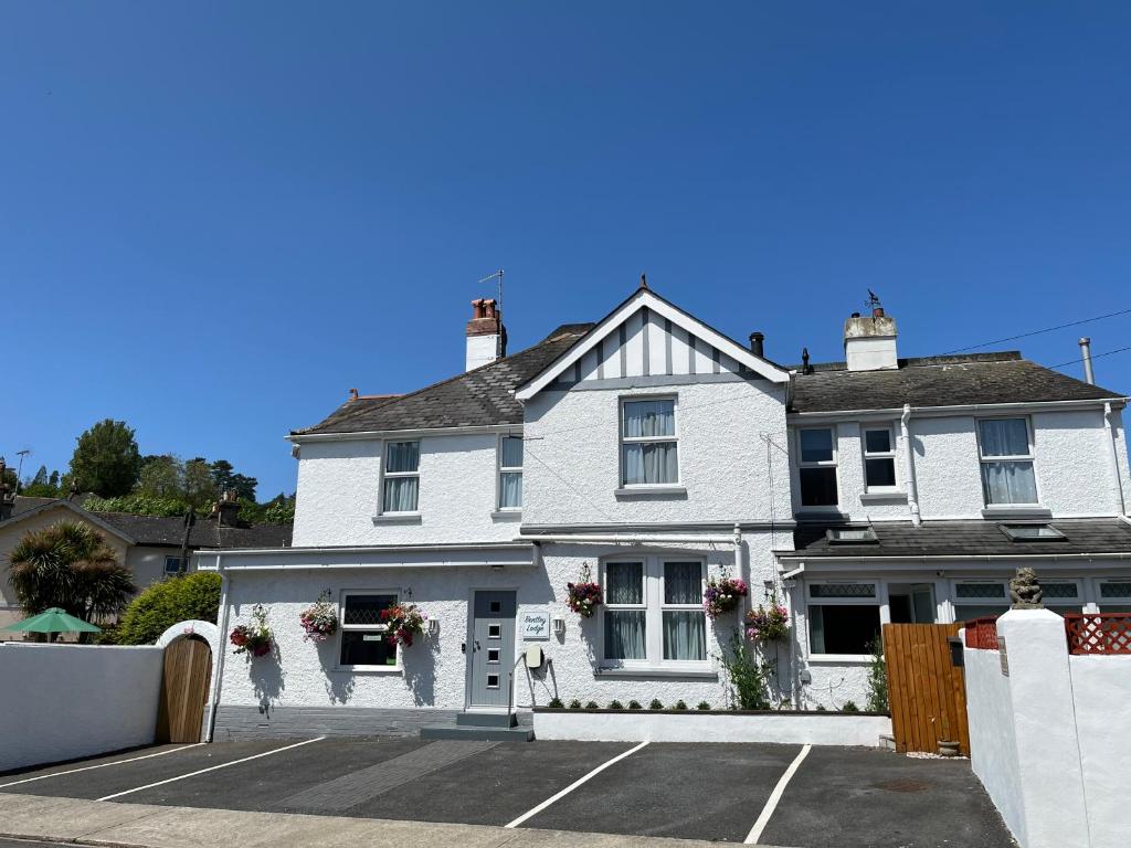 a white house with a parking lot at Bentley Lodge in Torquay