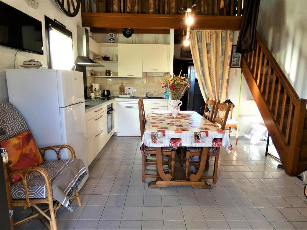 a kitchen with a table with chairs and a refrigerator at Aurus ii in Saint-Paul-lès-Dax