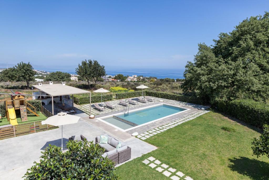 une cour avec une piscine et une pelouse avec des parasols dans l'établissement Lux Villa Mia with Heated Pool, 2km to Beach & Childrens Area!, à Mikro Metochi