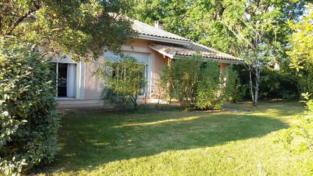 a small white house with a yard in front of it at Rose in Biscarrosse