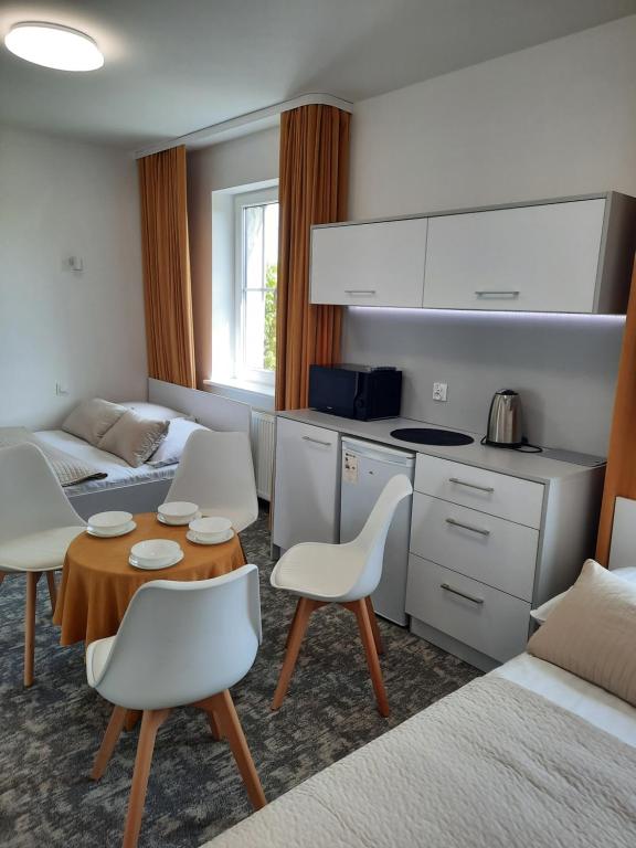 eine Küche und ein Wohnzimmer mit einem Tisch und Stühlen in der Unterkunft Dom Wczasowy KORMORAN Niechorze - 300m od plaży in Niechorze