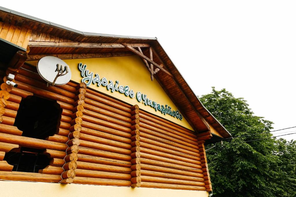 a log cabin with a sign on the side of it at Chudodievo in Chynadievo Mini-Hotel in Chynadiyovo