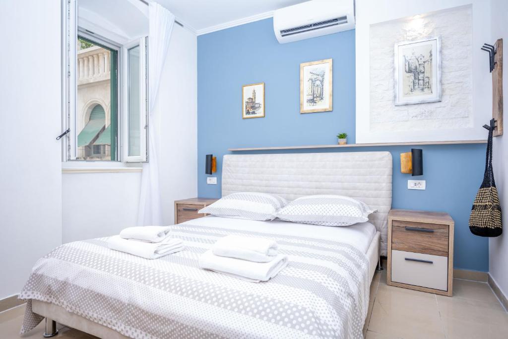 a blue bedroom with a white bed with two white towels at Apartment Bosanska in Split