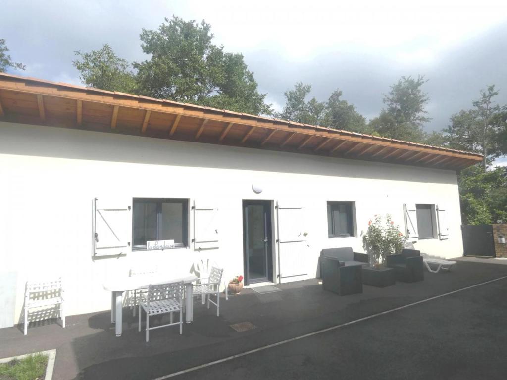 a white building with a patio with a table and chairs at La maison de mon grand-père, appt la landaise du lac in Léon
