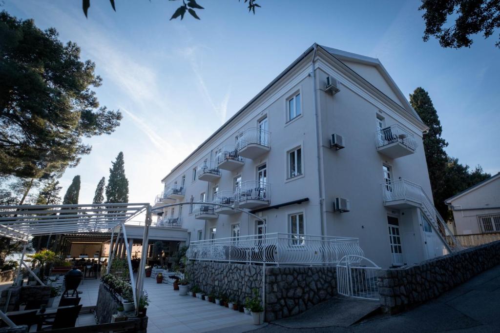 a large white building with a staircase leading up to it at Hotel Bor in Krk