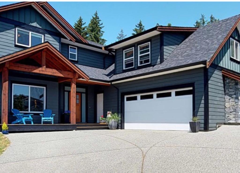 a blue house with a white garage door at Separate Suite in Prestigious Linley Valley in Nanaimo