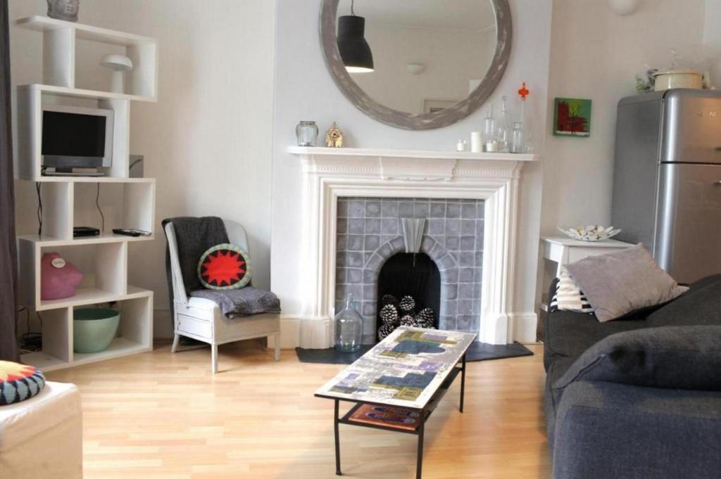 Trendy 2BD flat in West Hampstead في لندن: غرفة معيشة مع موقد ومرآة