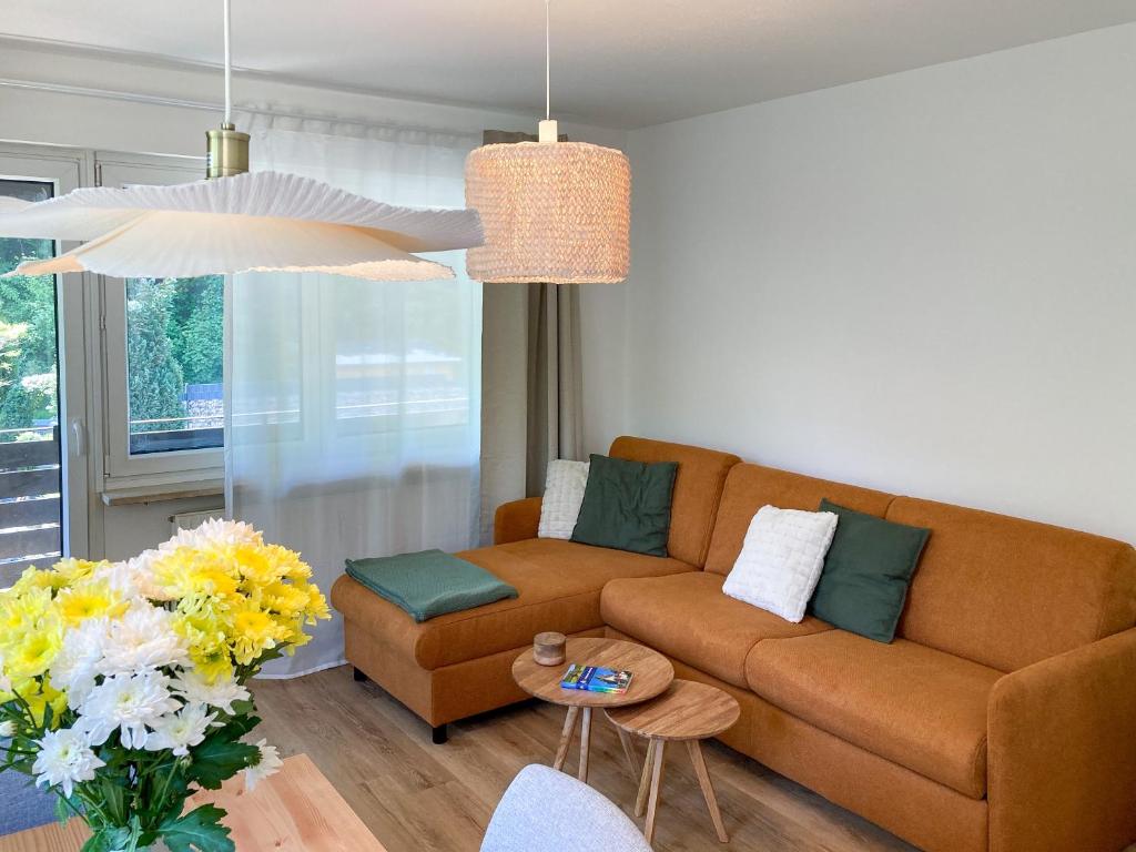 ein Wohnzimmer mit einem braunen Sofa und einem Tisch in der Unterkunft Kleines Glück zentral mit Balkon und Parkplatz in Gößweinstein