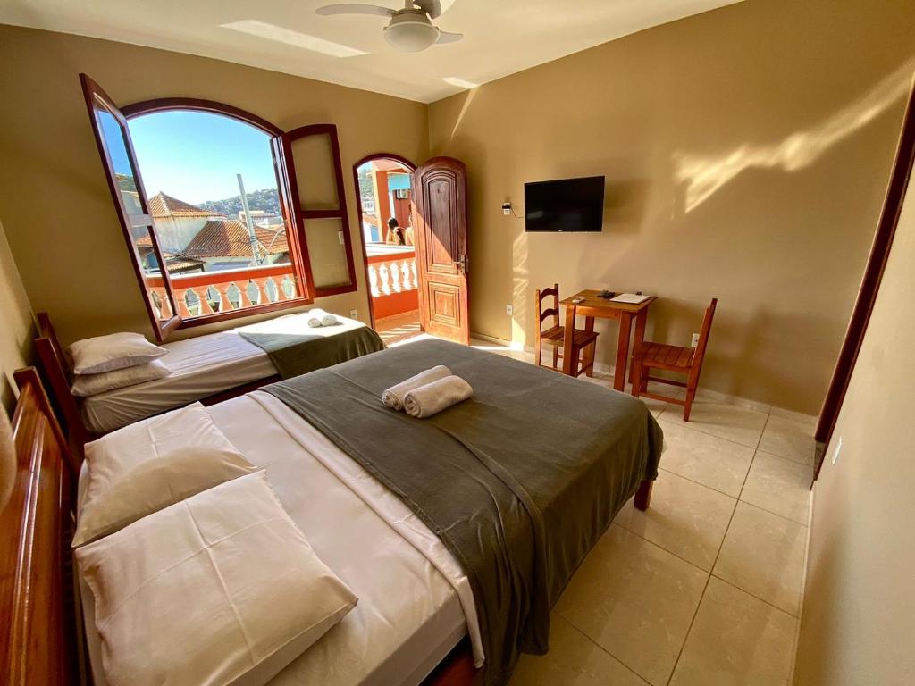 1 dormitorio con 2 camas, mesa y ventana en Pousada Paraíso dos Corais, en Arraial do Cabo