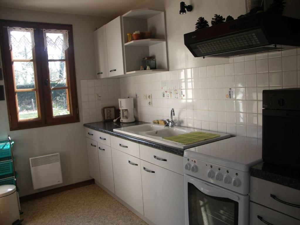 een witte keuken met een wastafel en een fornuis bij Le pin franc in Azur