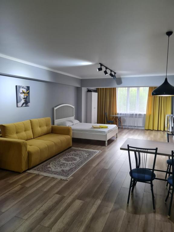 sala de estar con sofá amarillo y mesa en Апартаменты в центре, в новом доме, en Almaty