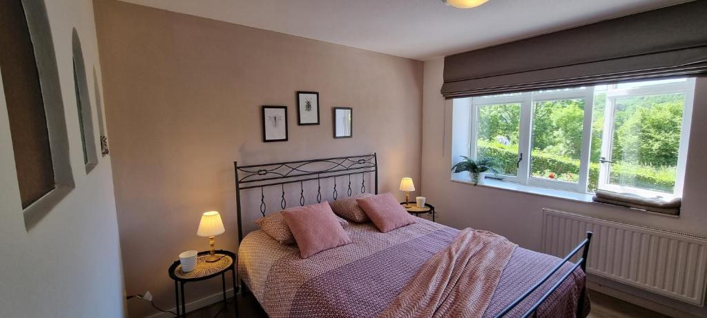 um quarto com uma cama com almofadas cor-de-rosa e uma janela em Gite ancienne Imprimerie em Bomal