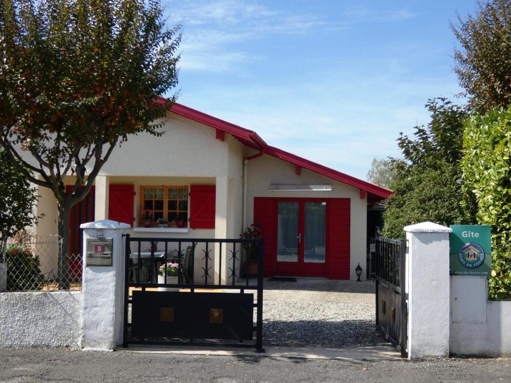 ein kleines rotweißes Haus mit einem Tor in der Unterkunft Jancelou in Peyrehorade