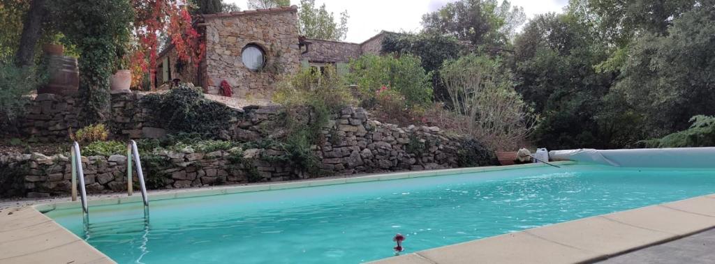 una piscina frente a una pared de piedra en Les jardins d'Isa en Tourves