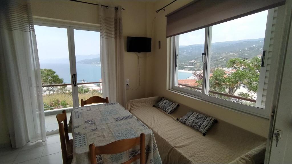 a dining room with a table and two large windows at Armenistis apartment in Armenistis