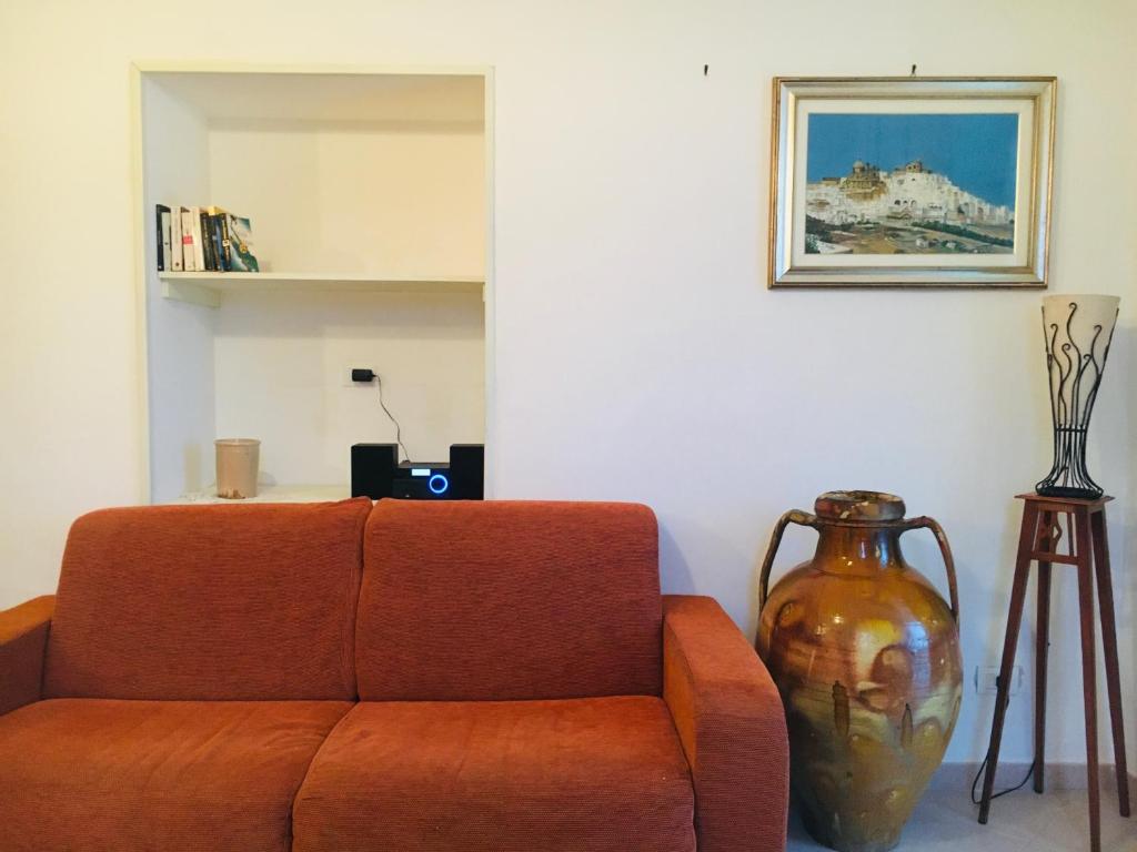 an orange couch in a living room with a vase at La Racioppola in Ostuni