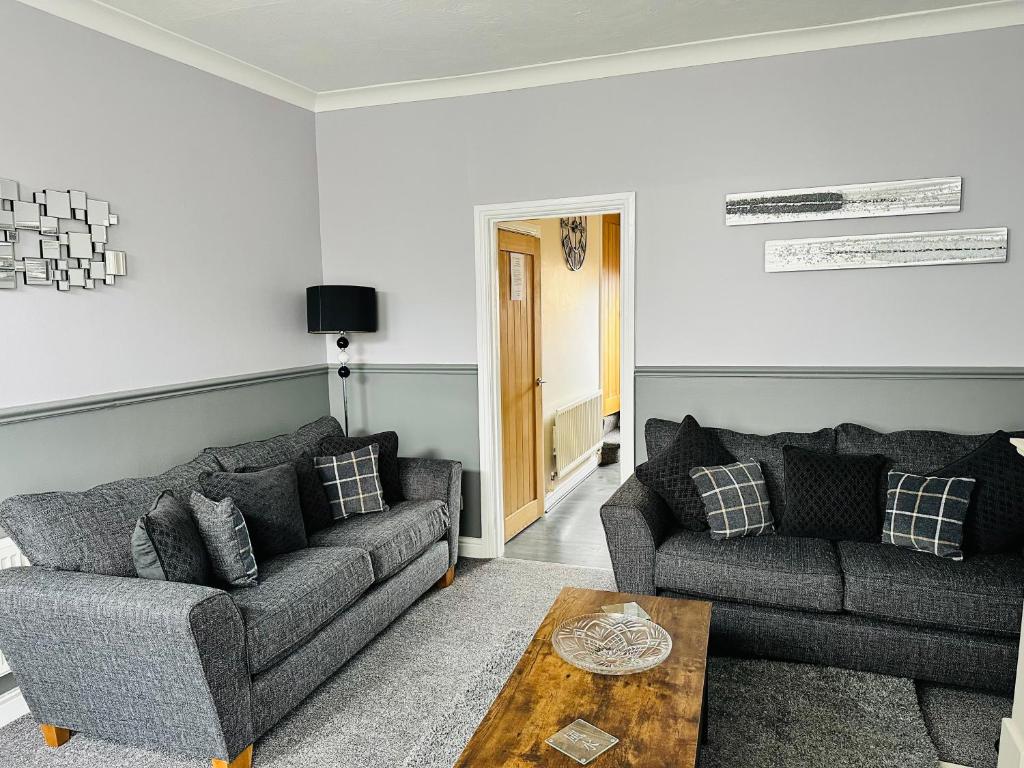 a living room with two couches and a table at Cosy house in Wombwell in Barnsley
