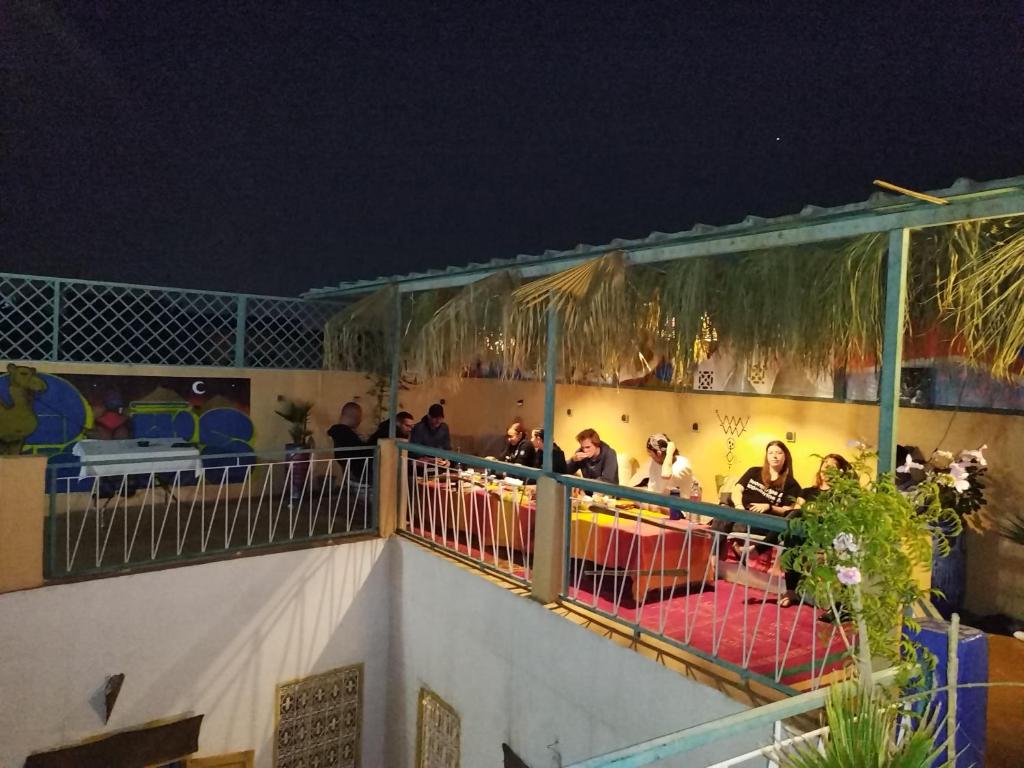 un gruppo di persone seduti su un balcone di notte di The Madrassa a Marrakech