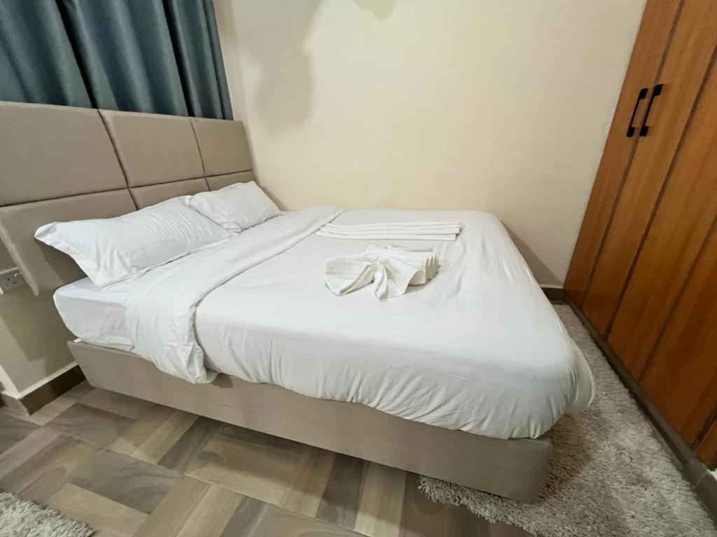 ein Bett mit weißer Bettwäsche und einem Bademantel darauf in der Unterkunft Urbantech 1 Bedroom Luxurious BnBs' in Nakuru