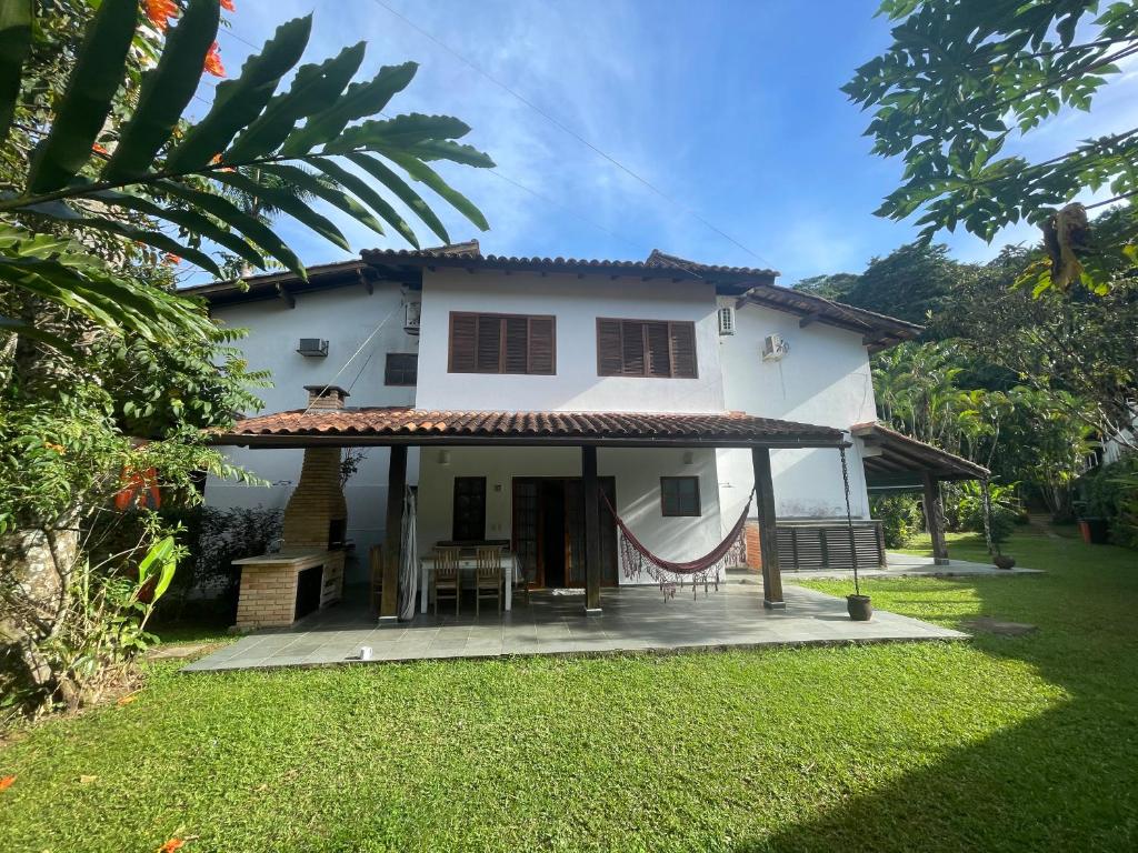 a white house with a porch and a lawn at Condominio Frente Praia Boissucanga in Boicucanga